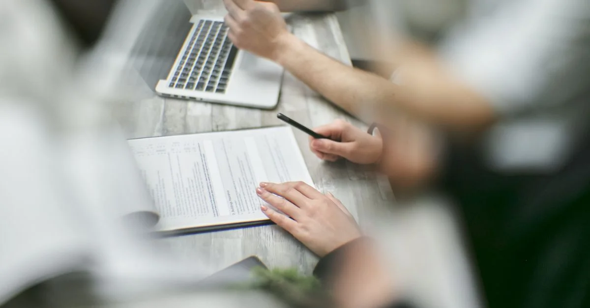 Vue en gros plan d'une équipe collaborant avec des documents et un ordinateur portable dans un environnement de bureau.